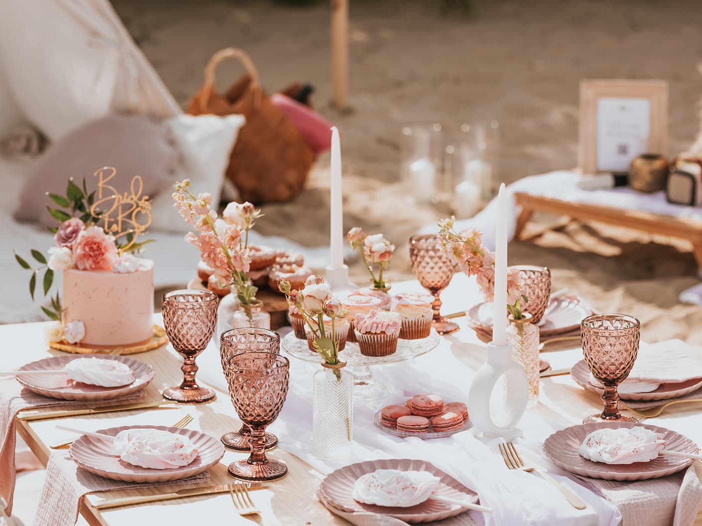 Elegancka różowa aranżacja piknikowa na plaży z deserami przygotowana przez event plannerkę