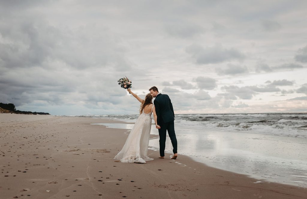 Nowożeńcy spacerujący po plaży o zachodzie słońca