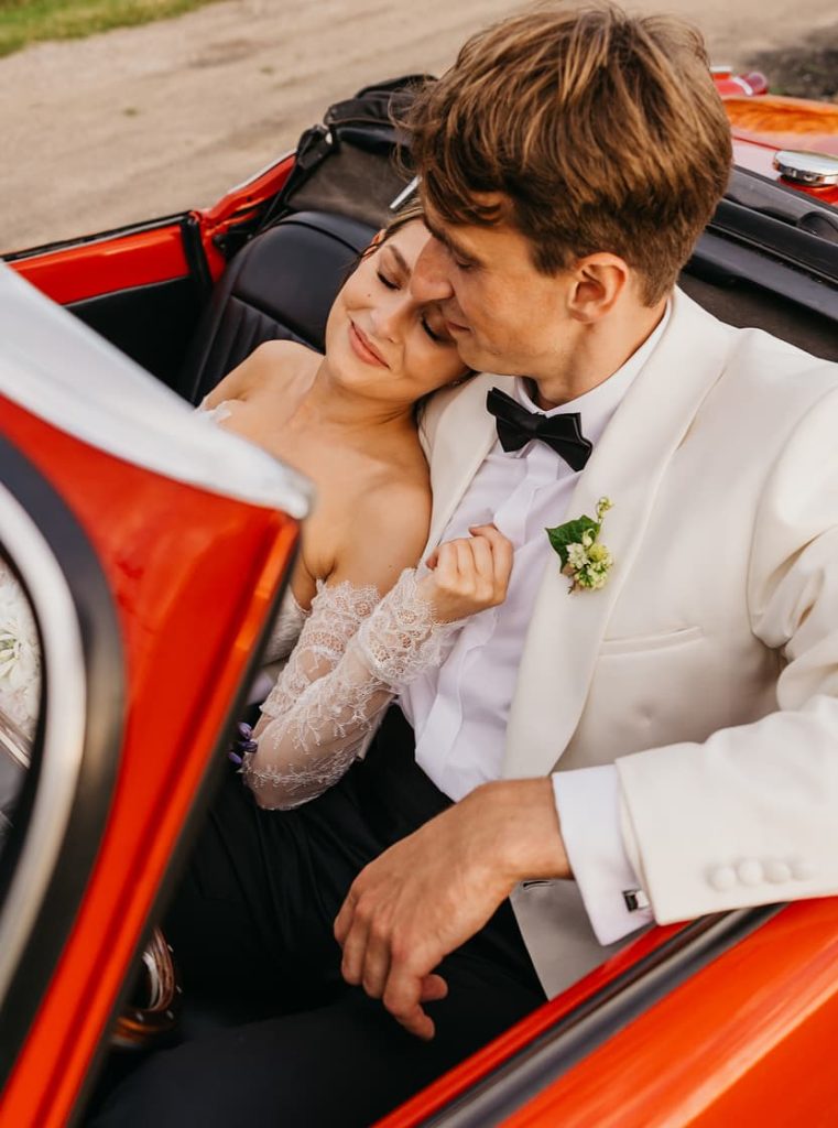 Nowożeńcy przytulający się w czerwonym kabriolecie