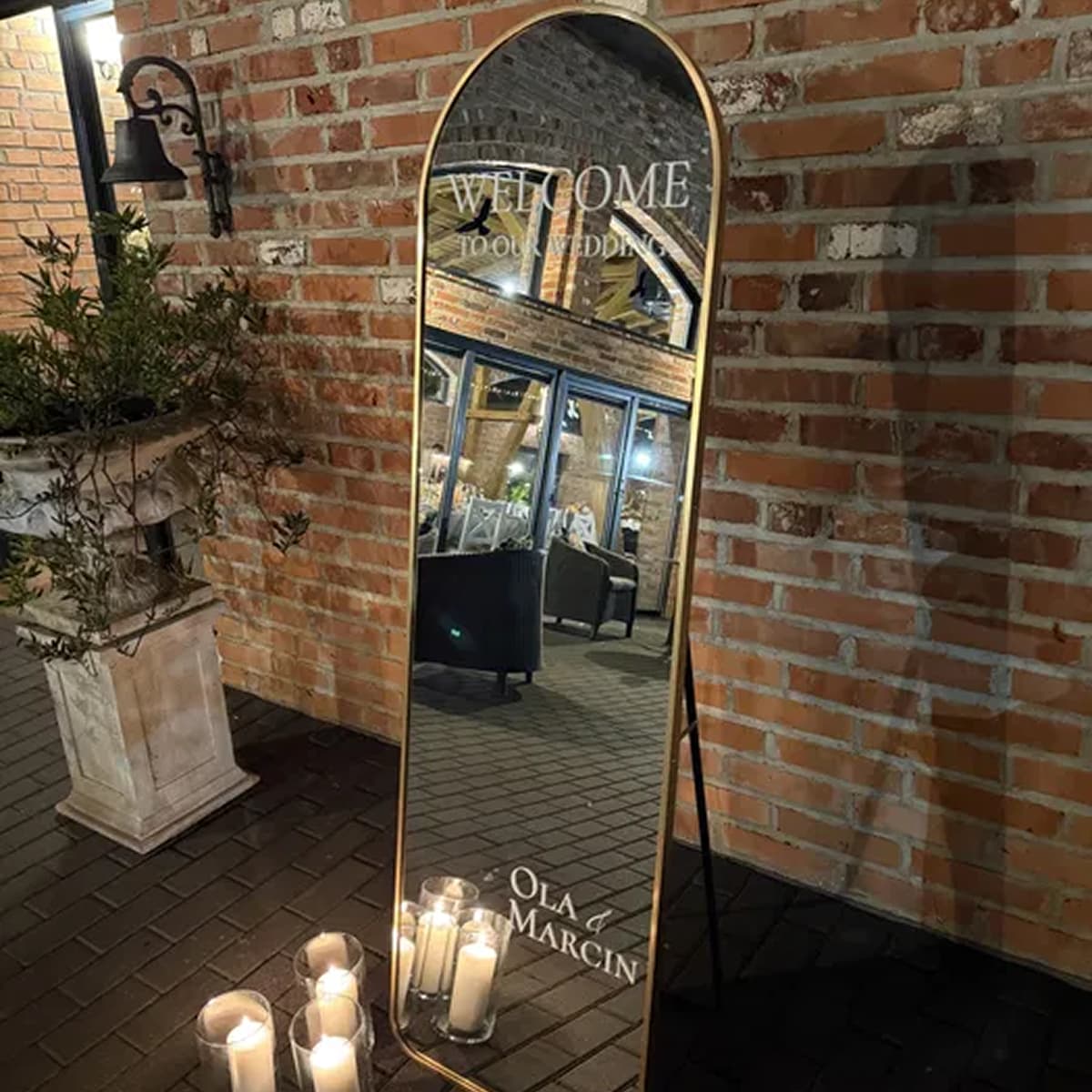 Lustro powitalne na wesele ze świecami przy ceglanej ścianie